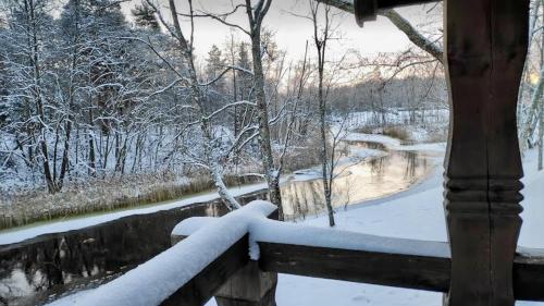 a fence covered in snow next to a river at Jõeääre puhkekeskus in Langa