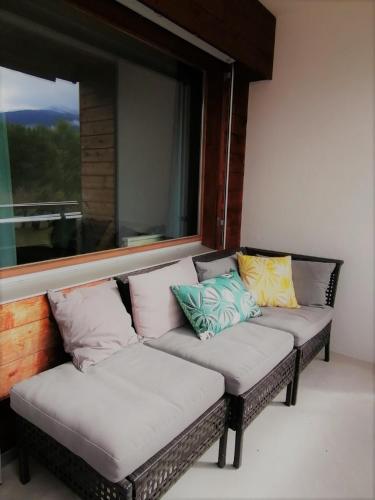 a couch with pillows sitting in a room with a window at LAAX Central Holiday Apartment with Pool & Sauna in Laax