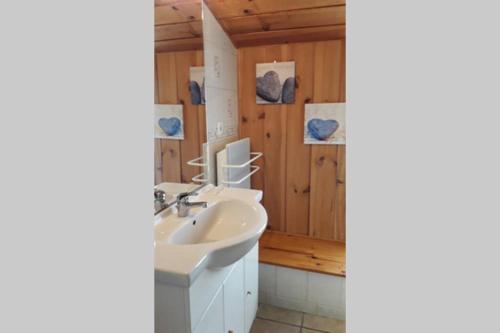een badkamer met een witte wastafel en een houten muur bij Ti Aval - Gîte de charme à la campagne - côte de granit rose in Bégard