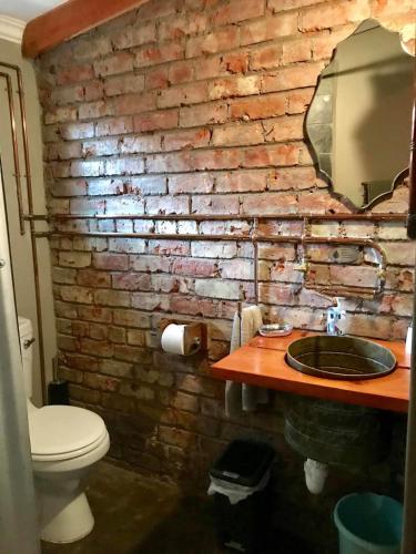 a brick wall in a bathroom with a toilet and a sink at RElaxed city living in Port Elizabeth