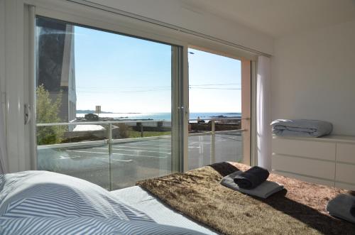 - une chambre avec un lit et une grande fenêtre en verre dans l'établissement Appartement Corniche II - Superbe Vue Mer !!! wir sprechen flieBen deutsch, Touristentipps, we speak English, à Concarneau