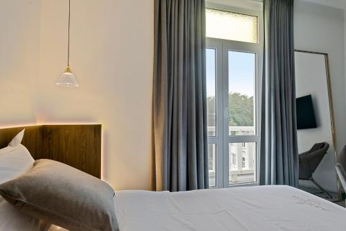 a bedroom with a bed and a large window at Hotel Astoria in De Haan