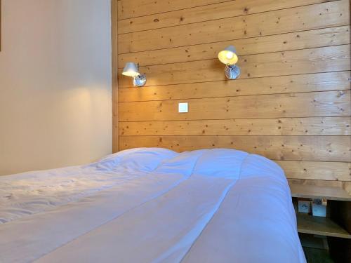 ein Schlafzimmer mit einem Bett mit einer Holzwand in der Unterkunft Appartement cozy centre Alpe d'Huez in L'Alpe-d'Huez