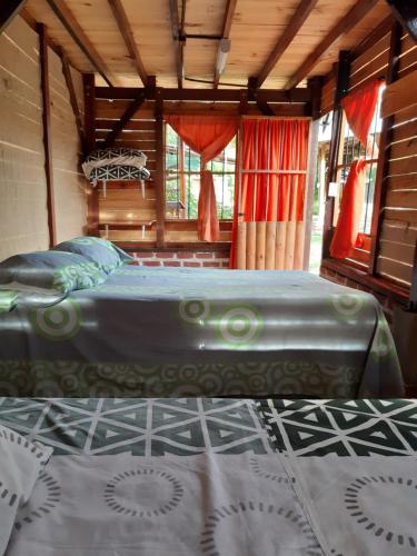 a bedroom with a bed in a room with windows at Finca el Morichal in Buga
