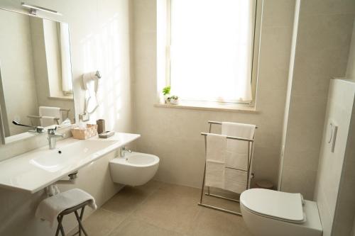 a white bathroom with a toilet and a sink at Hotel Europa in Dossobuono