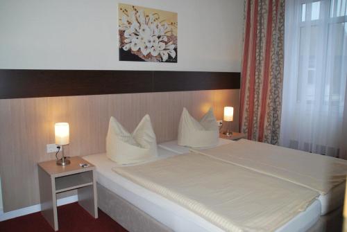 1 dormitorio con 1 cama grande, 2 mesas y 2 lámparas en Hotel Wuppertaler Hof en Remscheid
