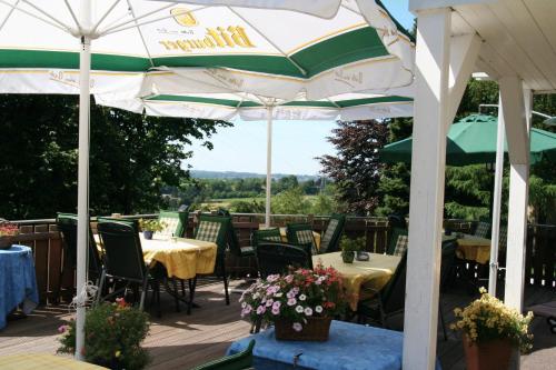 a patio with tables and chairs under an umbrella at Hotel Wuppertaler Hof in Remscheid
