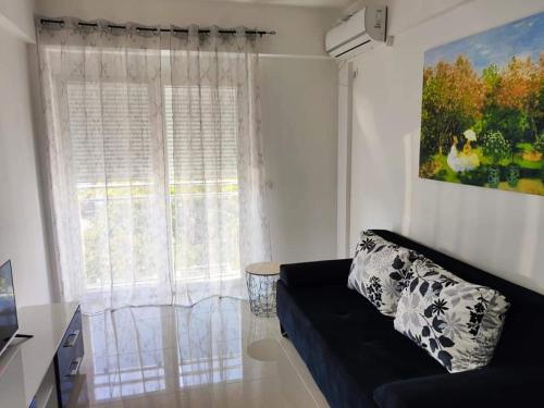 a living room with a black couch and a window at Vi studio city center 2min to sea in Bar
