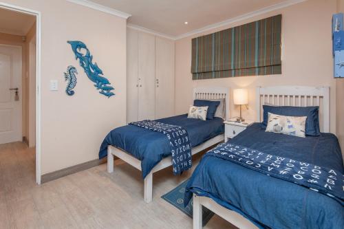 a bedroom with two beds with blue comforters at Hermanus Haven, entire home, on the sea, private pool, secure in Hermanus