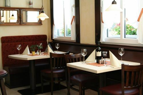 ein Restaurant mit zwei Tischen und Stühlen mit Weingläsern in der Unterkunft Hotel Wuppertaler Hof in Remscheid