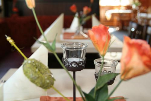 a table with two glasses and flowers on it at Hotel Wuppertaler Hof in Remscheid