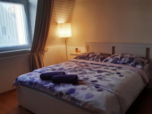 Un dormitorio con una cama con sábanas moradas y una lámpara. en Mona apartman, en Keszthely