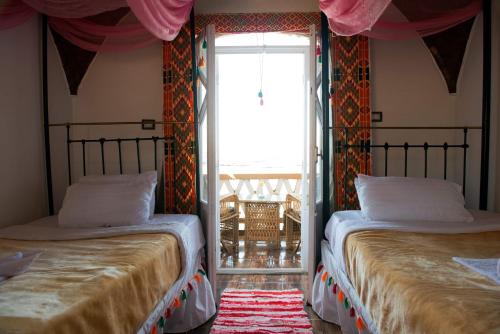 a bedroom with two beds and a window with a patio at Old Nubian guest house in Aswan