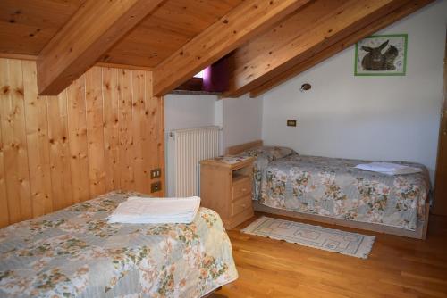 2 Betten in einem Zimmer mit Holzwänden und Holzböden in der Unterkunft Star Begn in Soraga