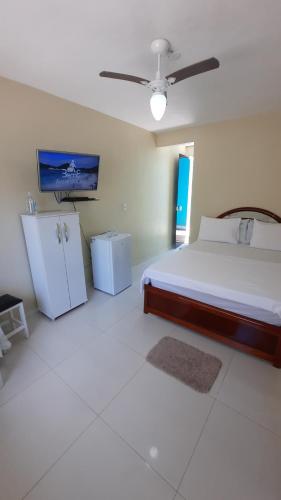 a bedroom with a bed and a tv on the wall at Seasun Suítes in Arraial do Cabo