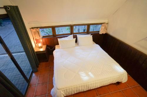 a bedroom with a white bed and a window at Baan Chai Dan in Thong Pha Phum
