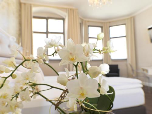 a vase filled with white flowers on a table at Lodner Hotel Drei Mohren in Lauingen