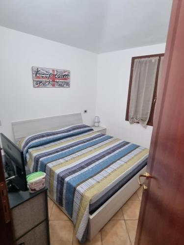 un letto con una coperta a righe sopra in una stanza di casa Federica a Olbia