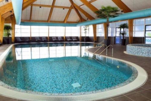 a large swimming pool with blue water in a building at Cube Exclusive Plus mit Meerblick am Strand im EuroParcs Bad Hoophuizen in Hulshorst