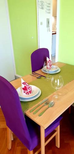 a table with purple chairs and a wooden table with plates at IstraNova Apartments in Rovinj
