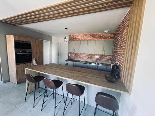 a kitchen with a counter with chairs around it at Maison en pierres au calme près d'Ancenis in Mésanger