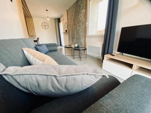 a living room with a couch and a flat screen tv at Maison en pierres au calme près d'Ancenis in Mésanger