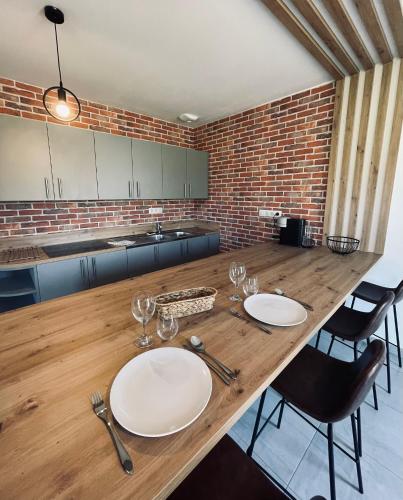 a kitchen with a wooden table with plates and wine glasses at Maison en pierres au calme près d'Ancenis in Mésanger