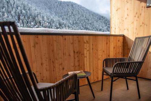 two chairs and a table on a balcony with a mountain at Hotel Gran Pre in San Vigilio Di Marebbe