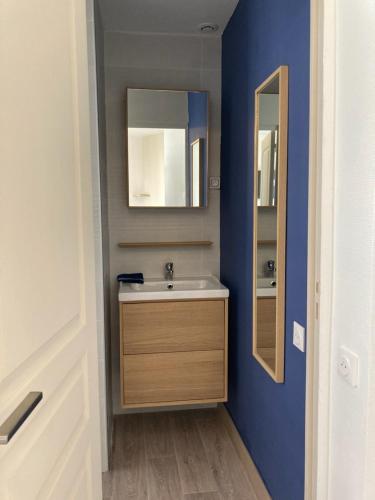 une salle de bain avec un lavabo et un miroir dans l'établissement La Capitane, à La Baule