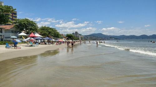 einen Strand mit Menschen und Sonnenschirmen und dem Meer in der Unterkunft Apto Frente Mar in Itapema