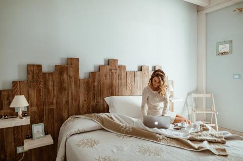 a woman sitting on a bed with a laptop at B&B Il Mare In Una Stanza in Ortona