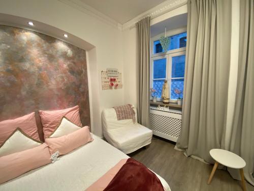 een slaapkamer met een bed, een raam en een stoel bij Marienzimmer in Weibern