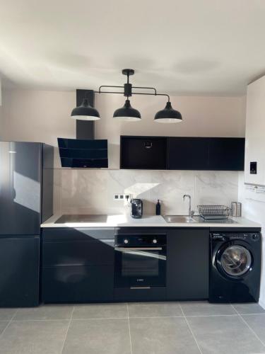 a kitchen with black cabinets and a washing machine at Le BEL AIR in Mont-de-Marsan