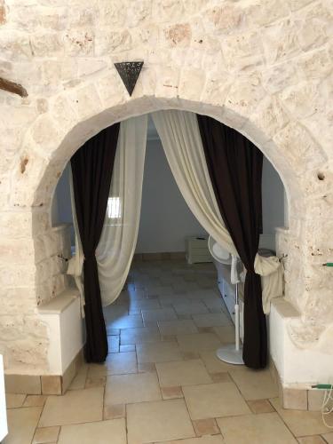 a room with a stone wall and curtains at Trullo Tita in Monopoli