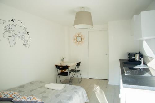 ein weißes Zimmer mit einem Bett und einem Tisch in der Unterkunft Au clos du bonheur in Saint-Sébastien-sur-Loire