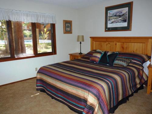 a bedroom with a bed with a striped blanket and windows at Austria Hof Lodge in Mammoth Lakes