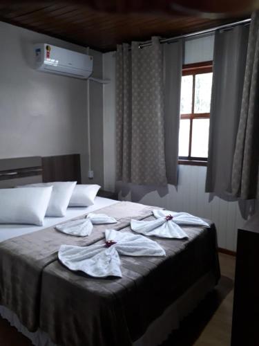 a bedroom with a bed with towels on it at Pousada Cravo e Canela SJ in São Joaquim