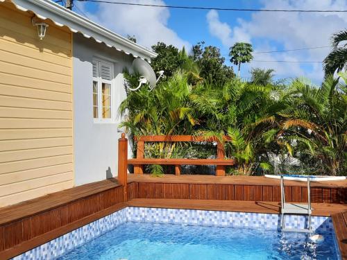 a house with a swimming pool and a wooden fence at LES MULTIPLIANTS in Le Moule