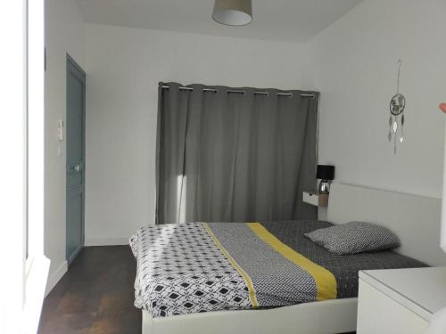 um quarto com uma cama com uma cortina cinzenta em T3 COSY REFAIT A NEUF PROCHE GARE em Perpignan