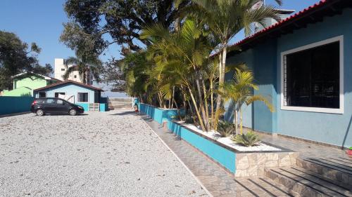 a car parked next to a blue house with palm trees at Pousada Cantinho D´Lilica in Balneário Praia do Leste