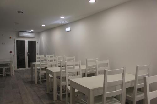 una sala da pranzo con tavoli bianchi e sedie bianche di Hotel Beatriz a Serpa