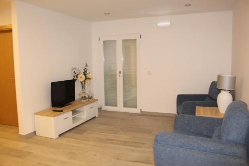a living room with two blue chairs and a television at Hotel Beatriz in Serpa