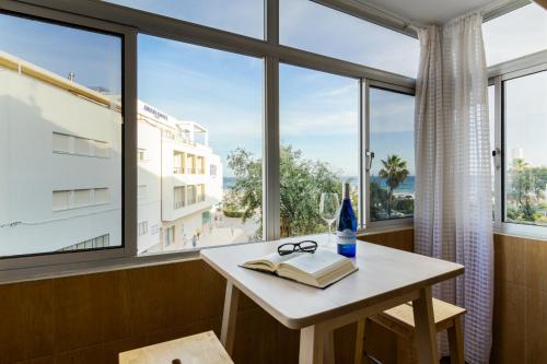 a table with a book and glasses on it in front of a window at Apartamento Murillo in Barbate