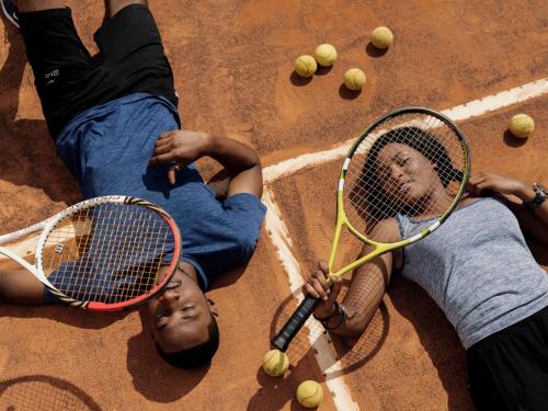 two boys laying on the ground with tennis rackets at Pullman Lubumbashi Grand Karavia. in Lubumbashi