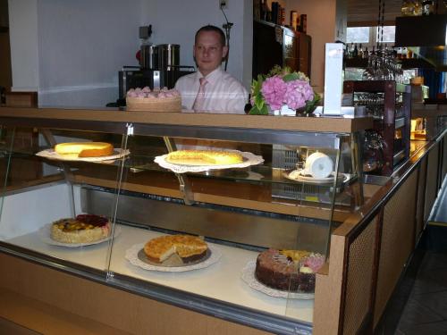 a man standing behind a display case with cakes at Hotel Zur schönen Aussicht in Grömitz