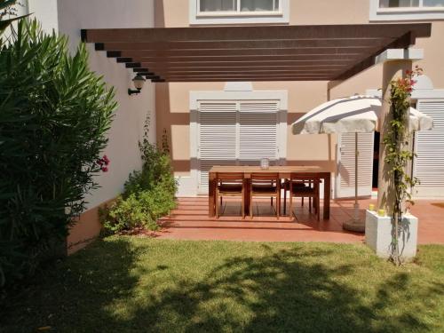 patio con tavolo in legno e ombrellone di Quinta do Lago Villa and Golf a Quinta do Lago