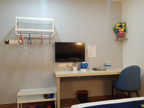 a room with a desk with a tv and a chair at GOOD 9 HOTEL - Cahaya Kota Puteri in Pasir Gudang