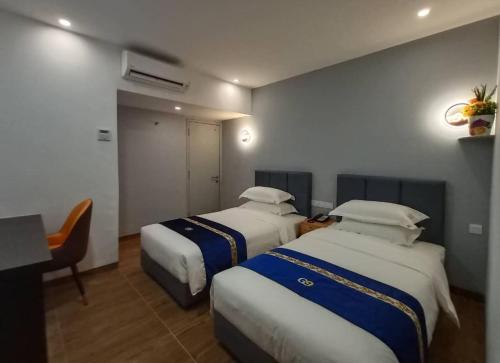 a hotel room with two beds and a desk at GOOD 9 HOTEL - Cahaya Kota Puteri in Pasir Gudang