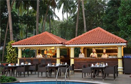 a restaurant with tables and chairs next to a pool at Park Inn by Radisson Goa Candolim in Candolim