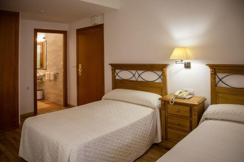 a bedroom with two beds and a phone on a night stand at Hotel Casa Ruba in Biescas
